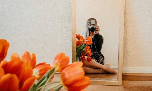 Stima de sine. Increderea in sine. Imagine de sine. Ce sunt si cum te influenteaza femeie in oglinda cu flori portocalii